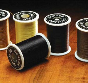 A group of spools of thread on top of a wooden table.